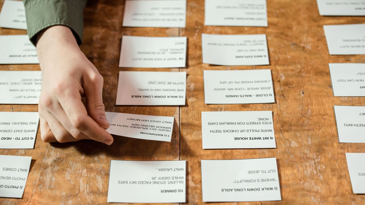 A person arranging cards with text on a wooden table.