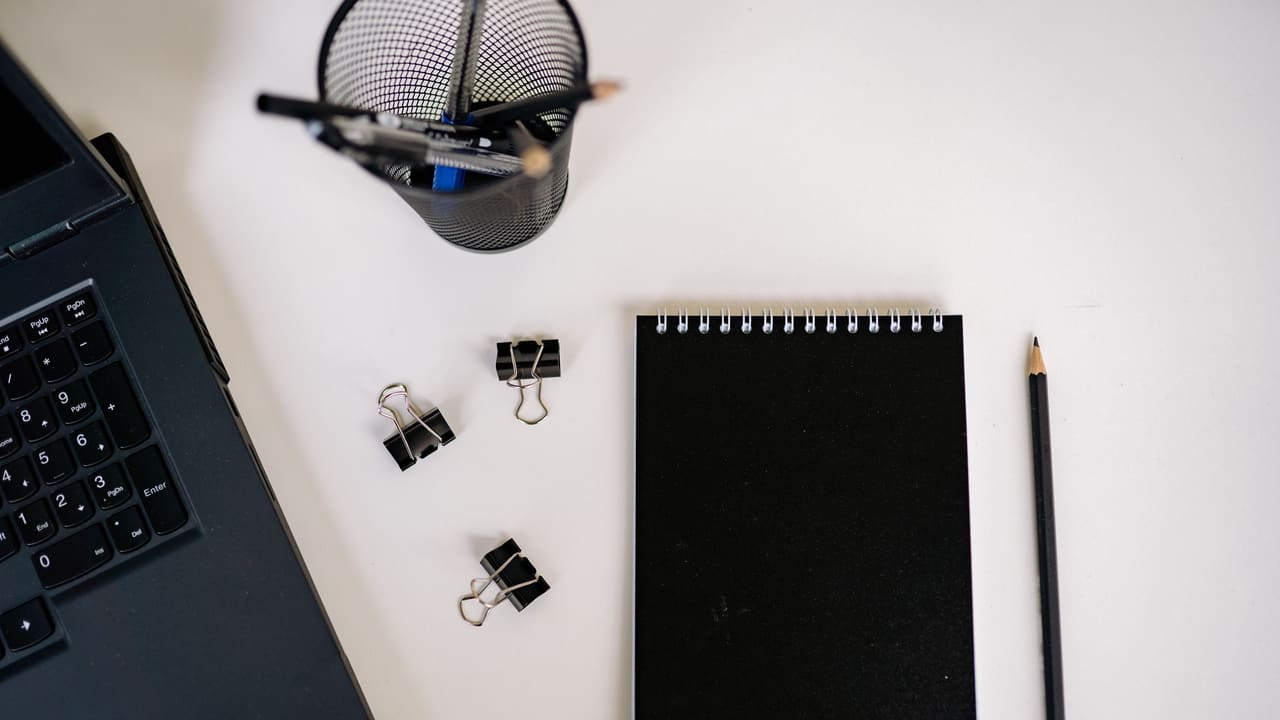 Modern office supplies, a notepad and a laptop, seen from above.