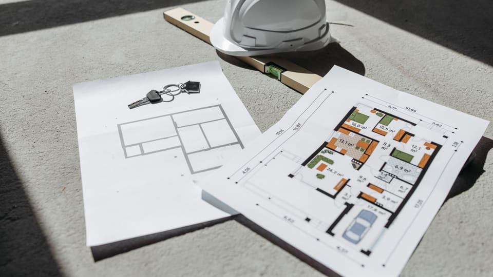 Architectural floor plans with helmet and keys on sunlit floor, perfect for real estate or construction themes.