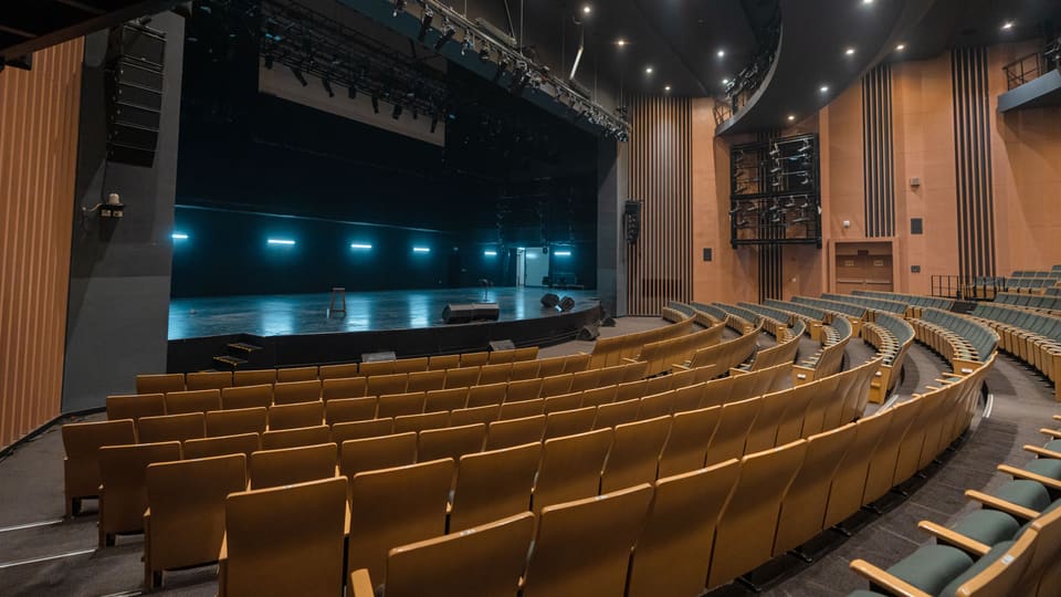 A wide view of an empty auditorium with a stage in Varanasi, India, ready for performance.