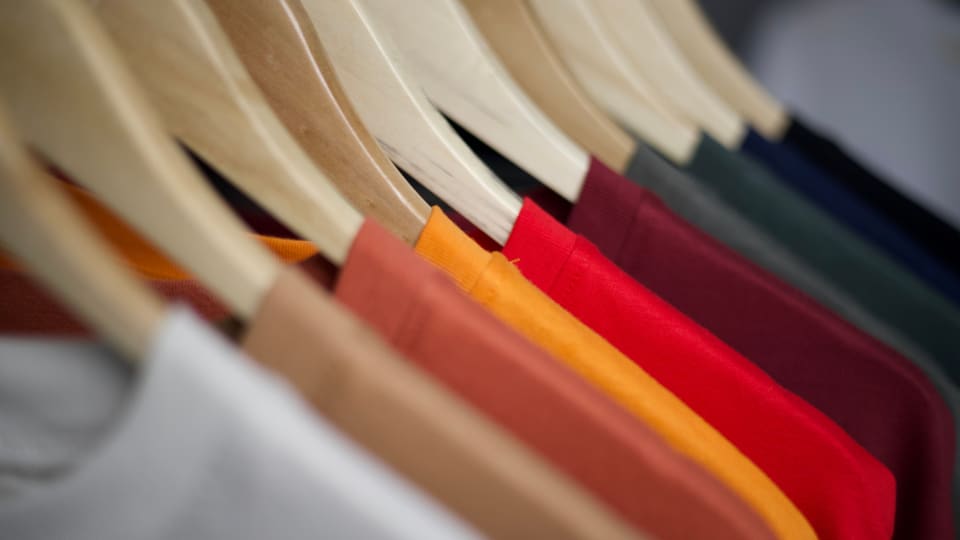 Close-up of colorful T-shirts arranged on wooden hangers, highlighting fashion display.