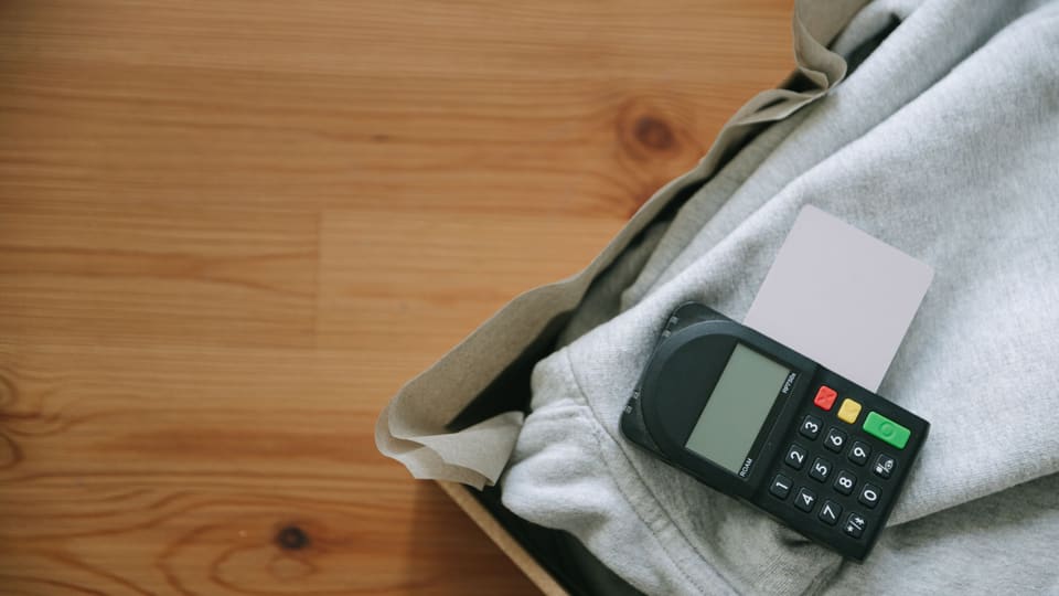 Close-up of payment terminal with credit card on grey clothing, ideal for retail concepts.