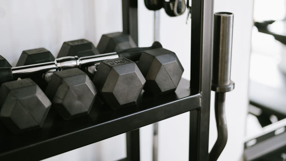 Close-up of gym equipment including dumbbells on a storage rack, perfect for fitness-themed uses.
