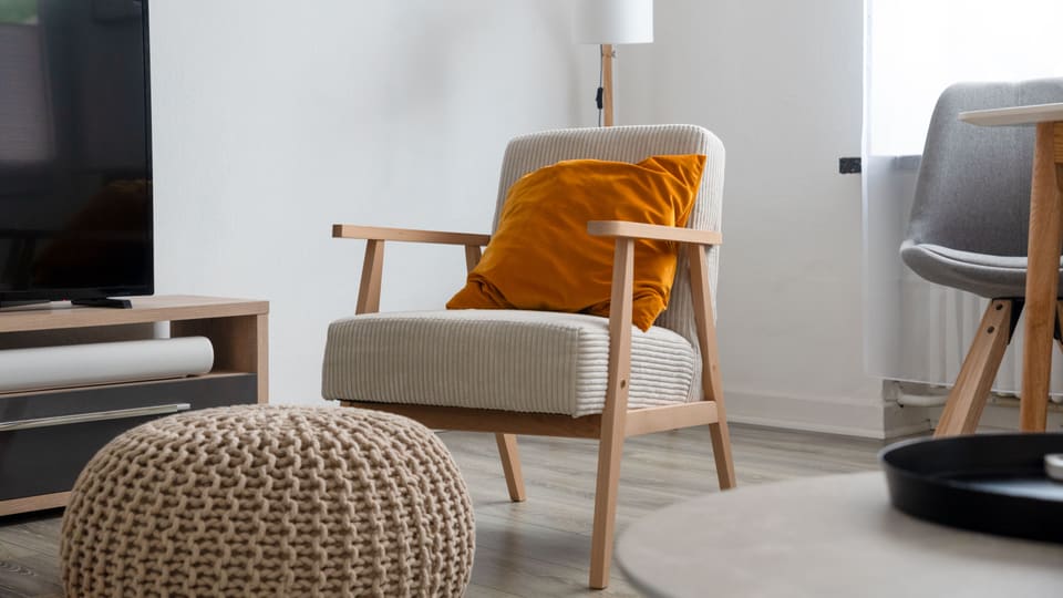 Modern living room interior featuring a comfy armchair, plush pillow, and sleek furniture.