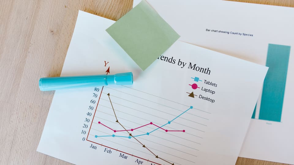 Desk with colorful graphs, sticky notes, and a marker, perfect for data analysis themes.