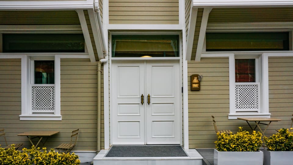 Charming entrance of a house featuring white double doors and outdoor seating.