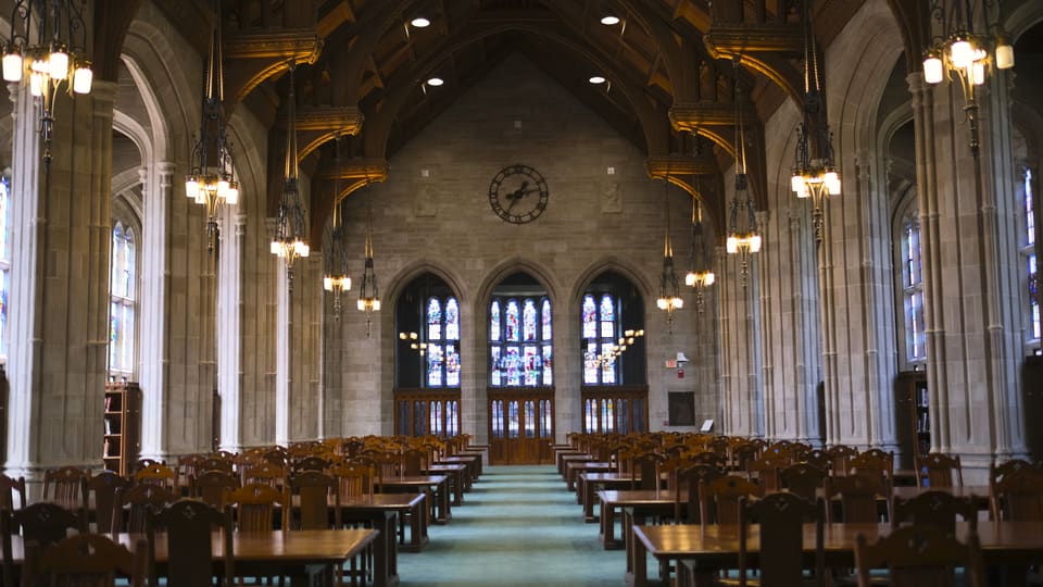 Quiet study area with wooden desks and stained glass in Boston's library.